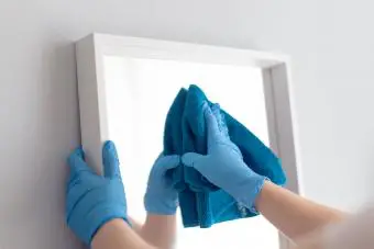 Mujer limpiando un espejo con un trapo