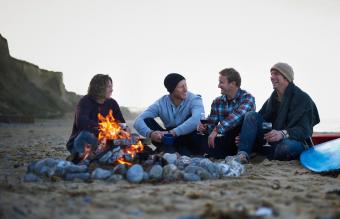 amigos sentados alrededor de un fuego abierto 