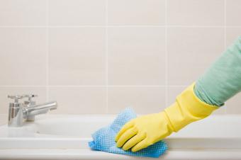 Mujer limpiando bañera con guantes