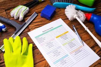 Suministros de limpieza alrededor del formulario del plan de limpieza semanal con bolígrafo