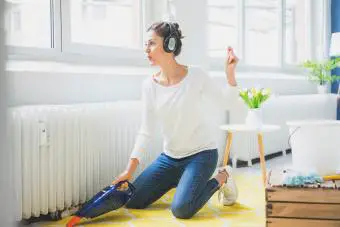 Mujer en casa usando audífonos aspirando el piso