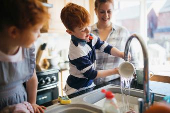 Dos niños y su madre lavando los platos.