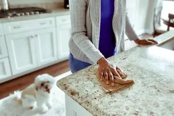 mujer limpia granito en la encimera de la cocina 