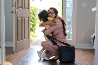 Una niña pequeña le da la bienvenida a su madre en la puerta cuando llega a casa del trabajo 
