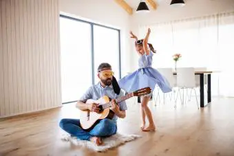padre e hija pequeña con guitarra adentro, divirtiéndose