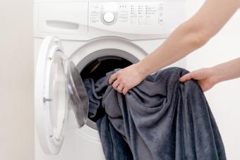 Las manos de la mujer ponen la ropa en la lavadora blanca