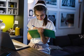 Jovencita estudiando mientras usa audífonos con cancelación de ruido