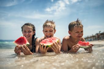 Niños felices comiendo sandía en la playa