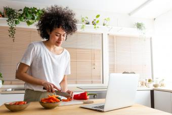 mujer cocinando siguiendo una receta en línea usando una laptop