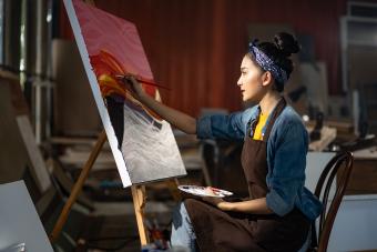 Mujer sentada frente a su gran cuadro sobre lienzo