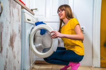 mujer usando una lavadora para lavar la ropa en casa