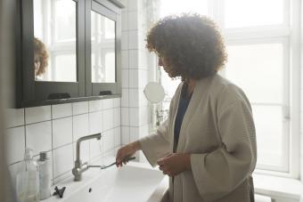 Mujer lavando el cepillo de dientes con agua corriente