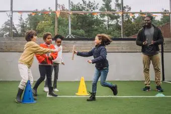 Profesor motivando a los estudiantes a hacer actividades deportivas en el patio de recreo
